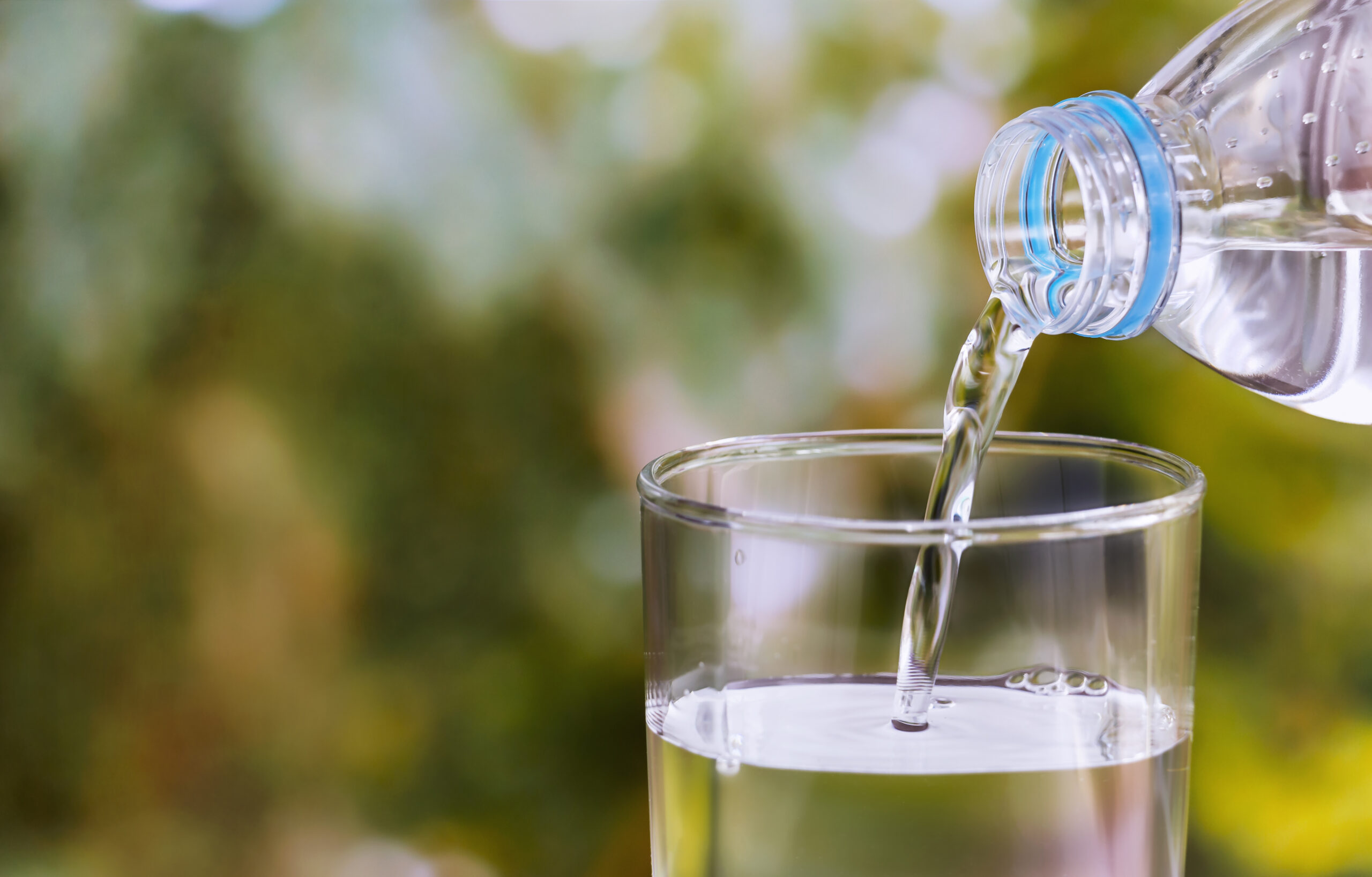 Pouring of clear drink water from bottle into the glass on blurr